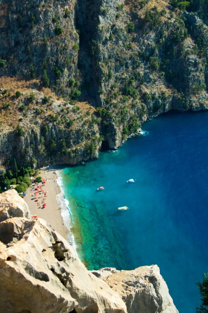 Turquoise water, a small beach and boats below steep coastal cliffs